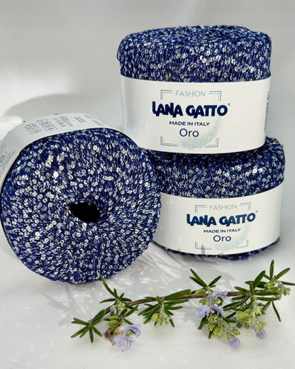 Two balls of blue yarn with white speckles and a jar labeled 'Lana Gatto' on a white background.