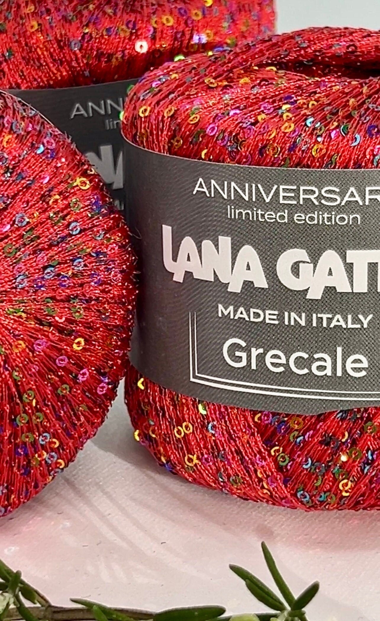 Red yarn skein with colorful sequins and 'Lana Grossa' label on a white background