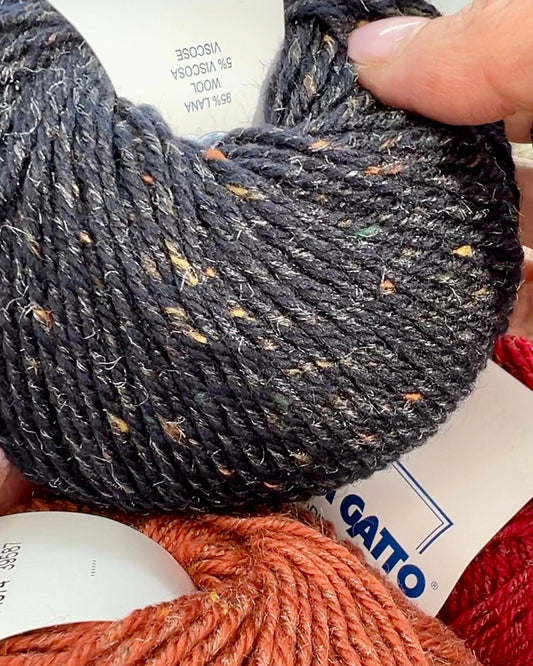 Close-up of iDOKNiT Lana Gatto EVEREST tweed yarn, showing the rustic texture of the Merino and Viscose blend with signature colorful neps in a 50g ball.