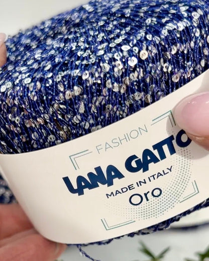 Blue and silver glitter yarn with 'Lana Gatto' label held by a hand