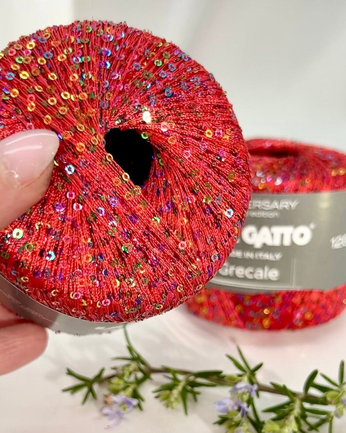 Red sequined scrunchie held by a hand with a white background