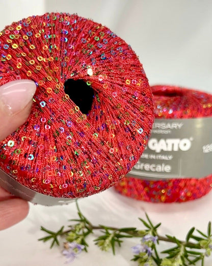 Red sequined scrunchie held by a hand with a white background