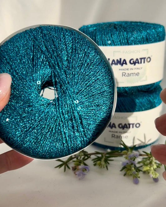 Blue glitter yarn spool with 'Mama Gatto' label on a white background