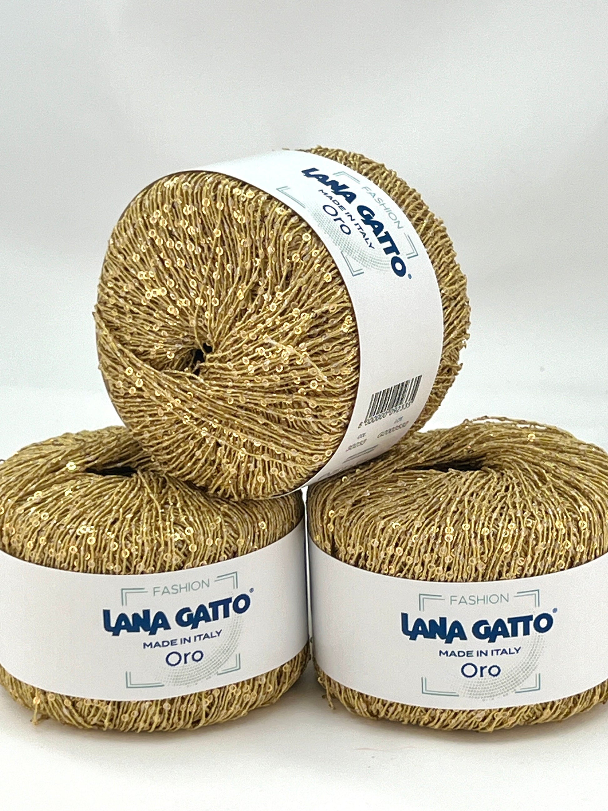 Three skeins of gold yarn with 'Lana Gatto' labels on a white background