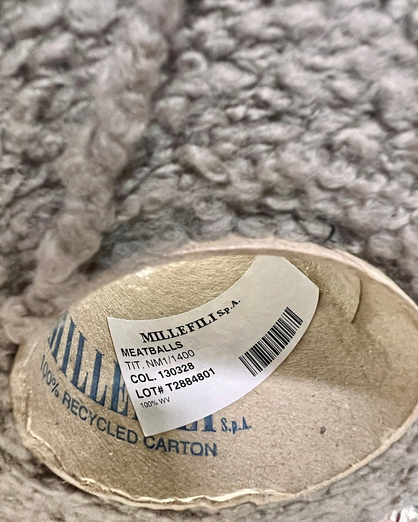 Millefili spa label on a recycled carton with a textured gray background