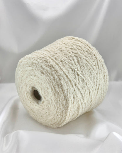 Roll of white yarn on a white fabric background