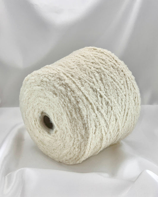Roll of white yarn on a white fabric background