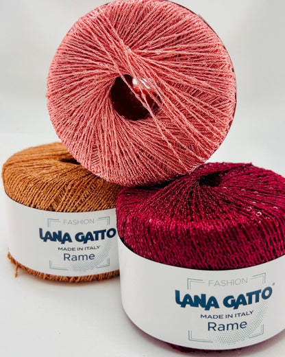 Two skeins of Lana Gatto yarn, one pink and one red, on a white background.