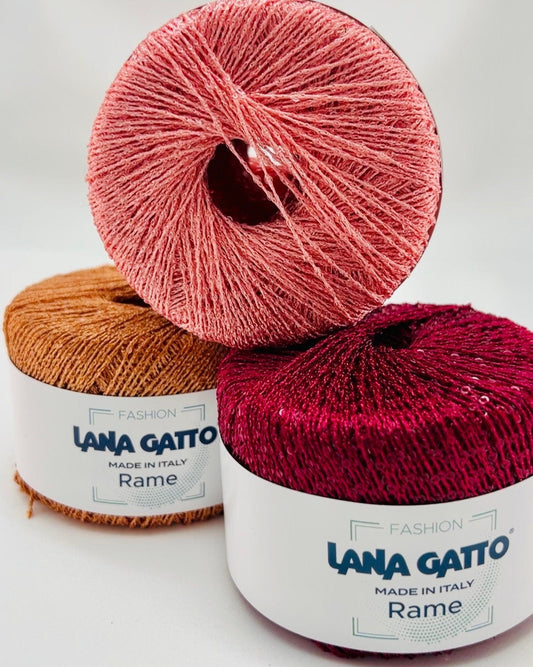 Two skeins of Lana Gatto yarn, one pink and one red, on a white background.