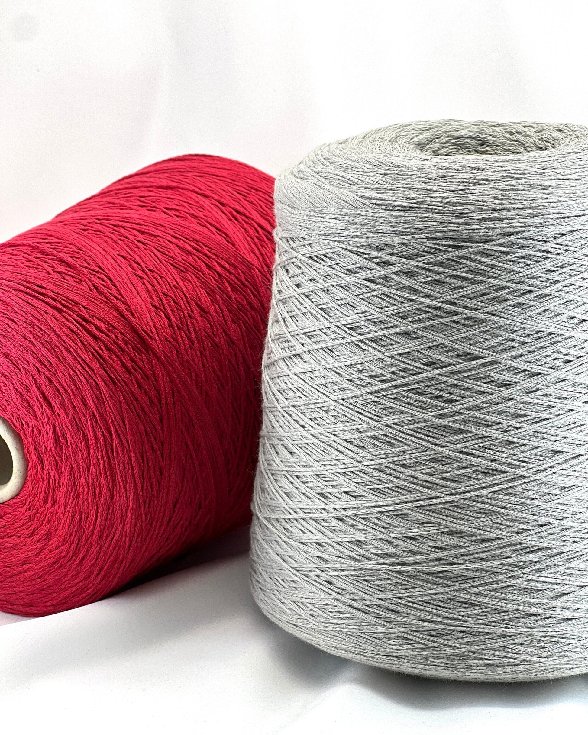 Two spools of yarn, one red and one gray, on a white background
