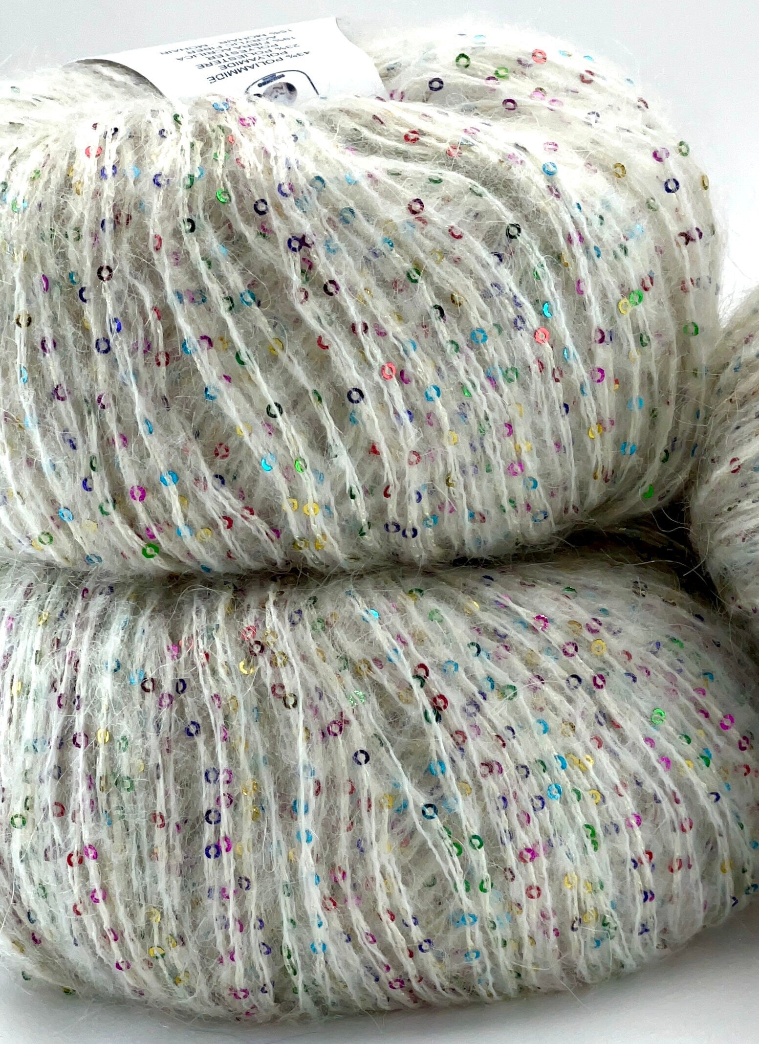 Two skeins of yarn with multicolored speckles on a white background