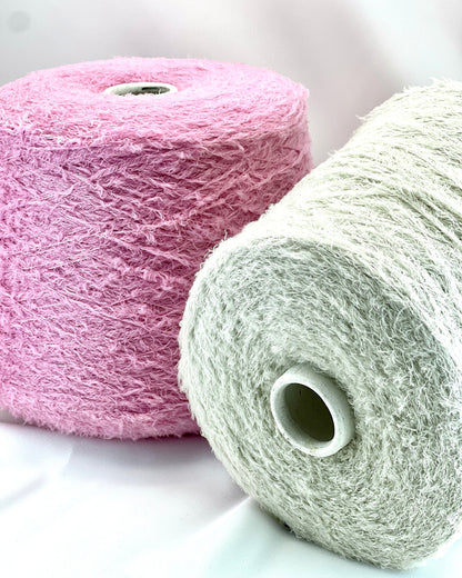 Two rolls of yarn, one pink and one white, on a light background