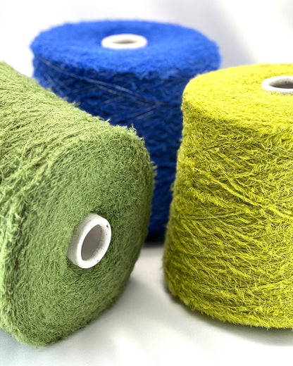 Three rolls of yarn in blue, green, and yellow on a white background