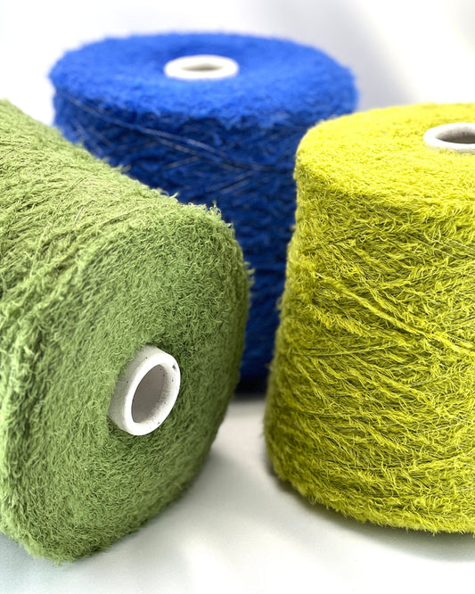 Three rolls of yarn in blue, green, and yellow on a white background