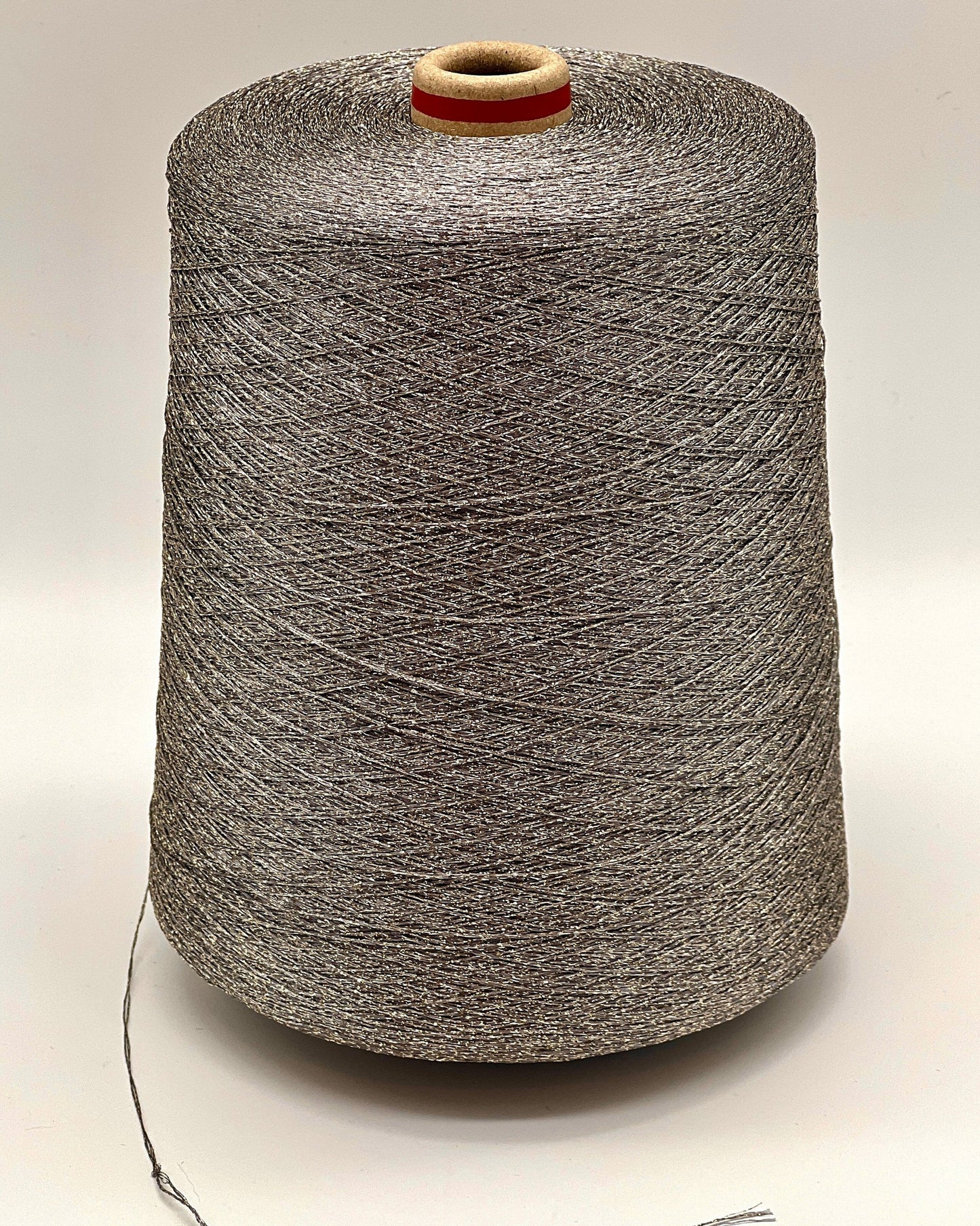 A professional cone of Kyototex MANNA-GROSSA metallic lamé yarn in Brushed Gold. The image shows the yarn's intense shimmer and fine texture, with detail shots of the fiber being held to demonstrate its lace-weight scale. Available at iDOKNiT.com.