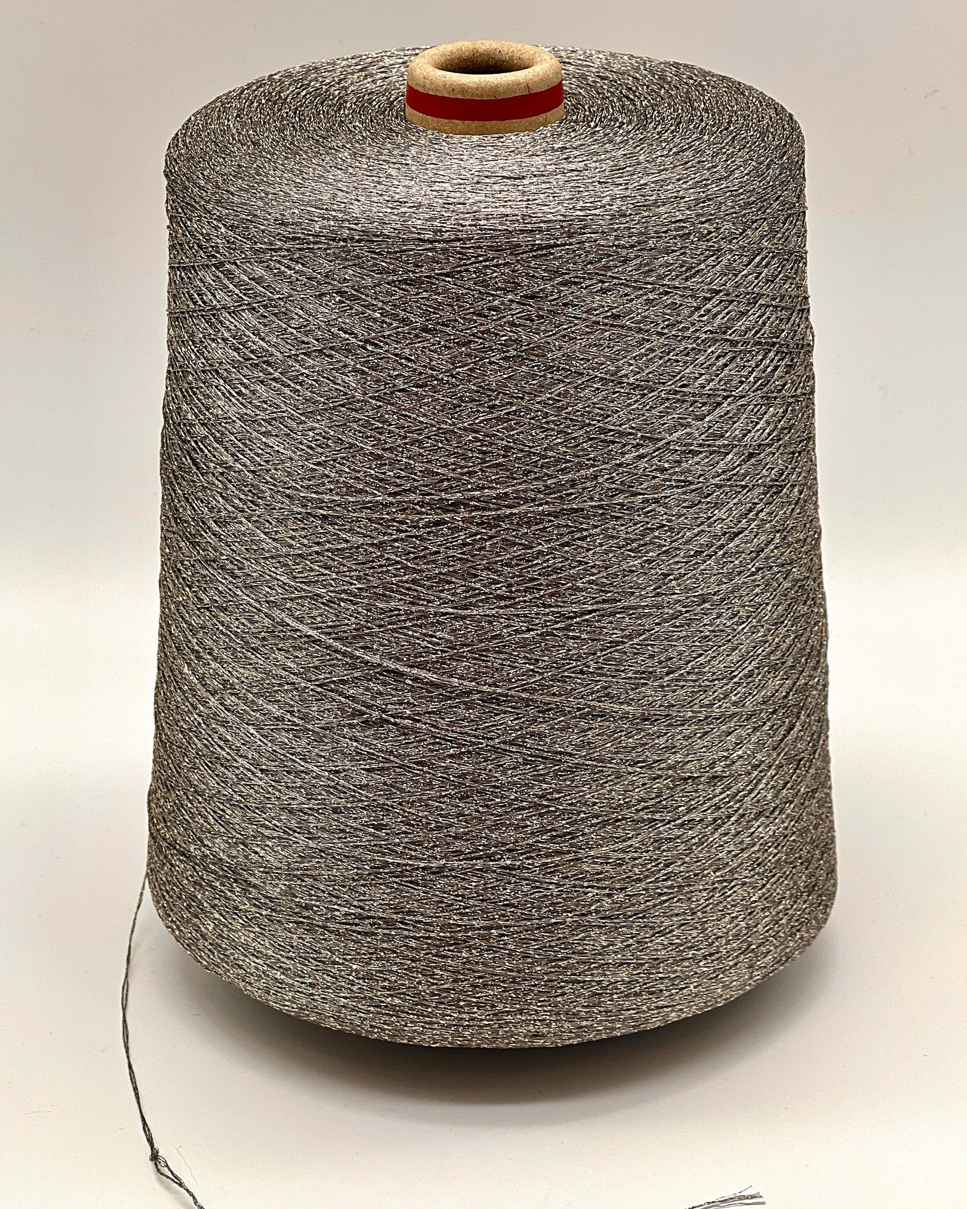 A professional cone of Kyototex MANNA-GROSSA metallic lamé yarn in Brushed Gold. The image shows the yarn's intense shimmer and fine texture, with detail shots of the fiber being held to demonstrate its lace-weight scale. Available at iDOKNiT.com.