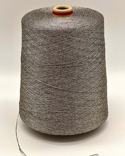 A professional cone of Kyototex MANNA-GROSSA metallic lamé yarn in Brushed Gold. The image shows the yarn's intense shimmer and fine texture, with detail shots of the fiber being held to demonstrate its lace-weight scale. Available at iDOKNiT.com.
