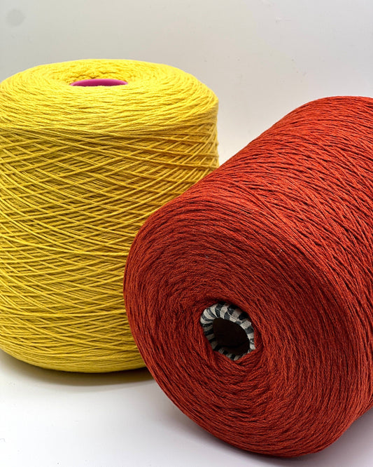 Two spools of yellow and red yarn on a white background