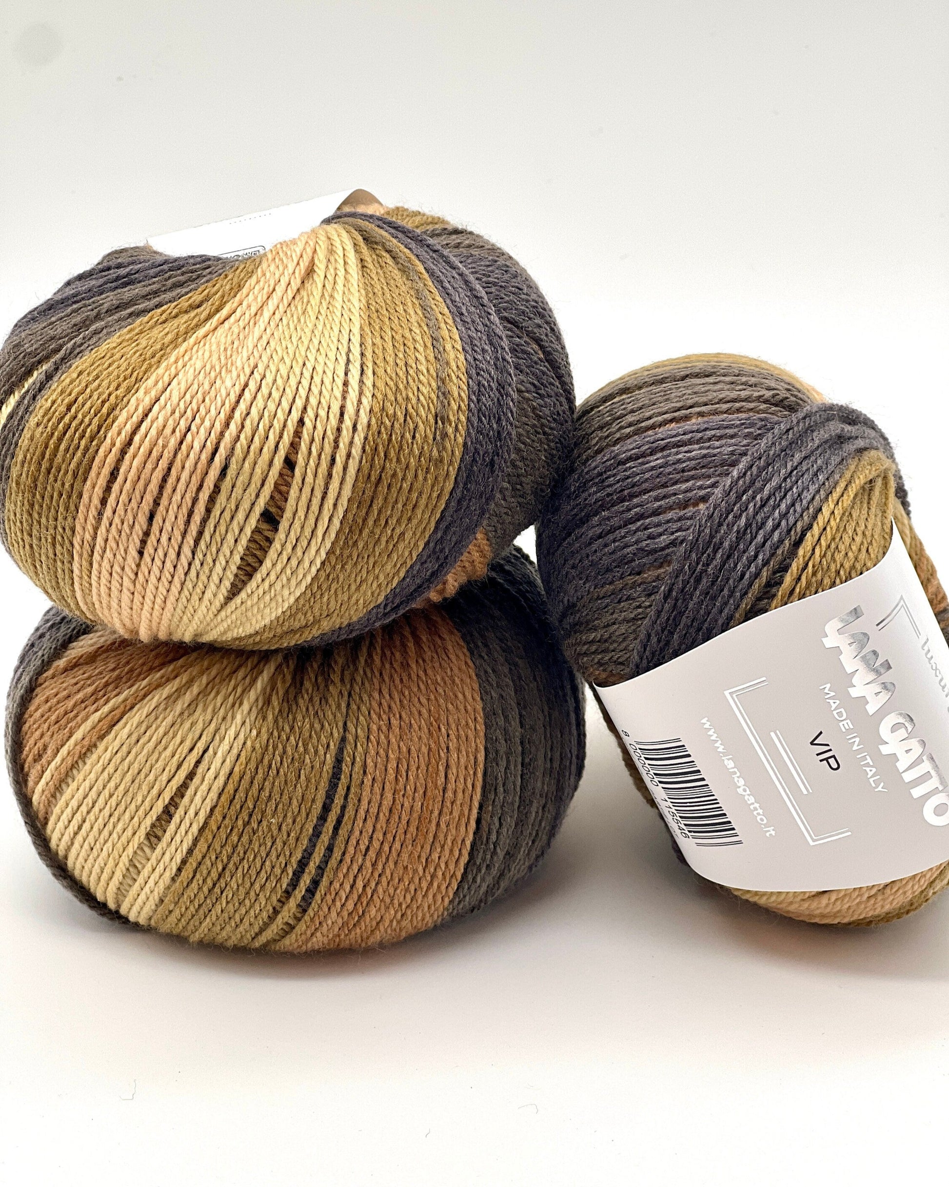 Three skeins of yarn in brown and gray tones on a white background