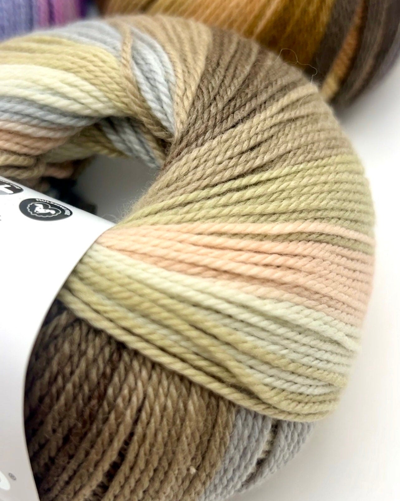 Ball of multicolored yarn with a visible brand label on a white background