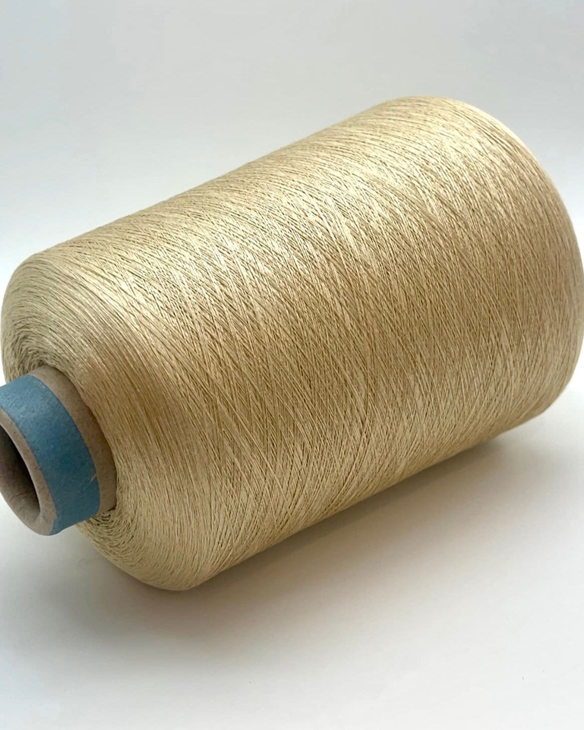 Spool of beige thread on a white background