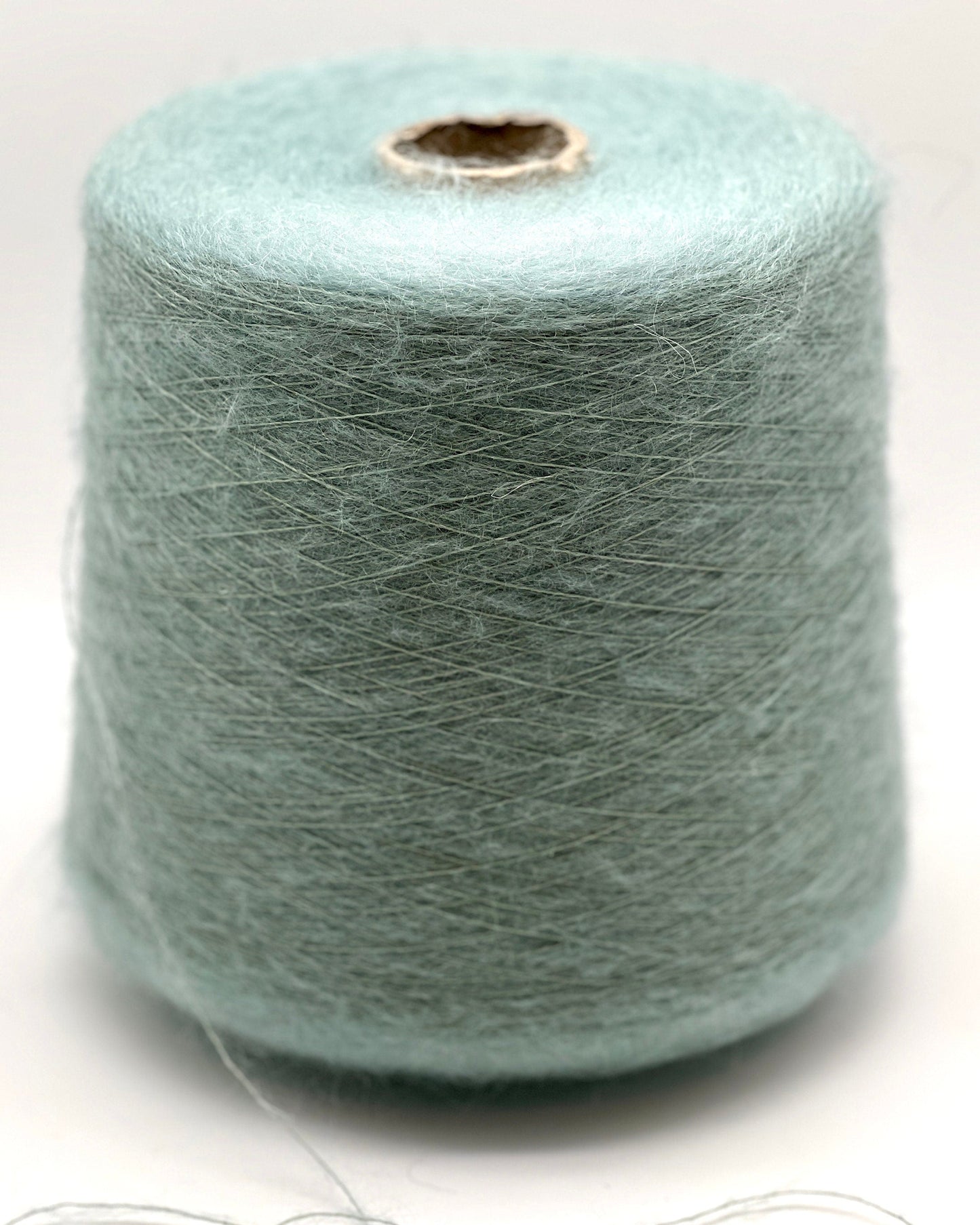 Spool of light blue yarn on a white background