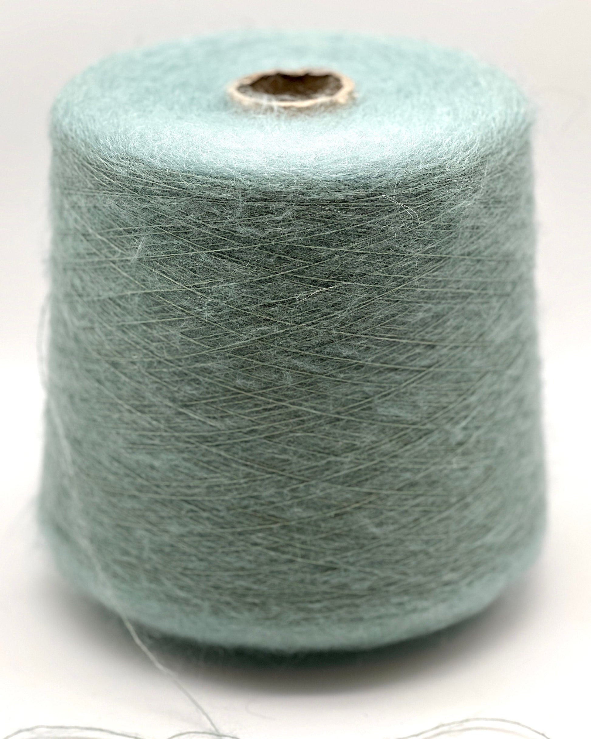 Spool of light blue yarn on a white background