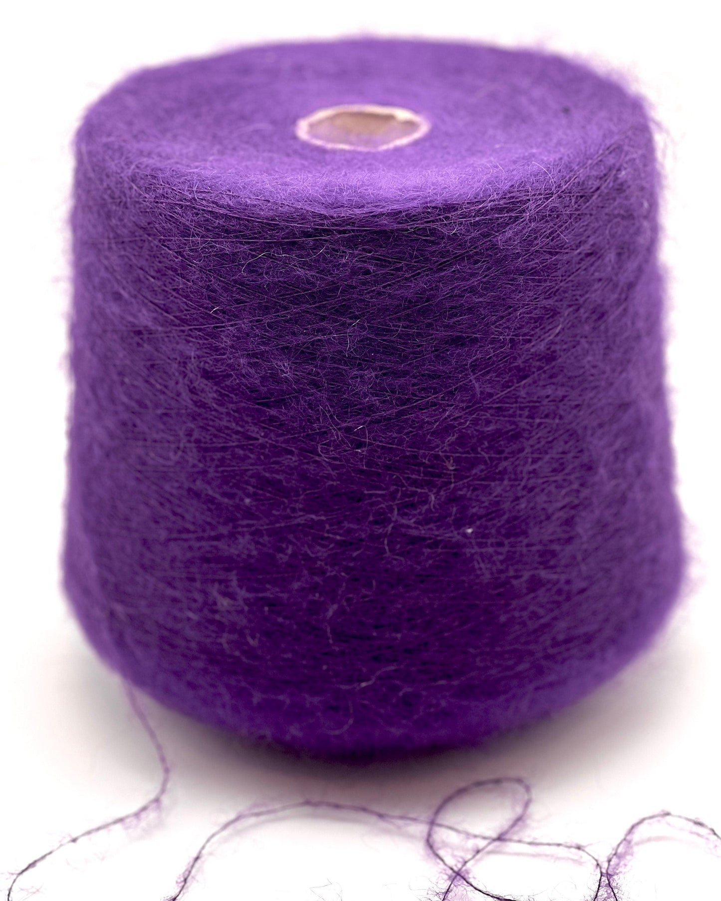 Purple yarn spool with some strands on a white background