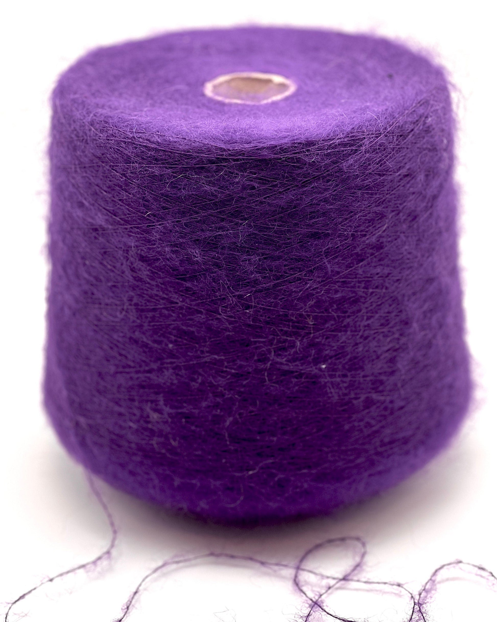 Purple yarn spool with some strands on a white background