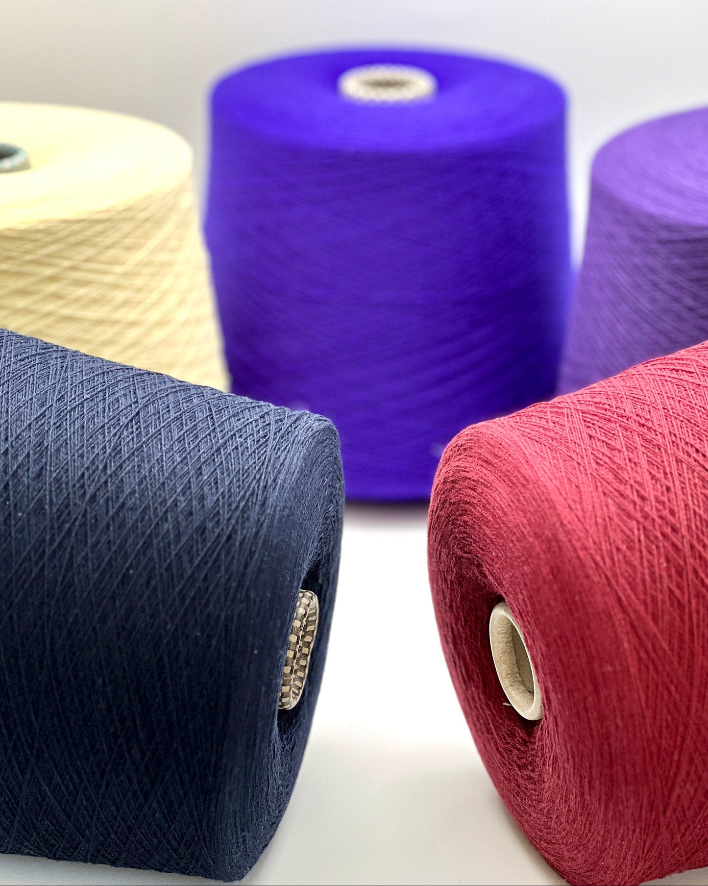 Four spools of yarn in different colors on a white background