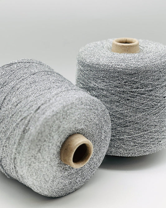 Two spools of silver yarn on a light gray background
