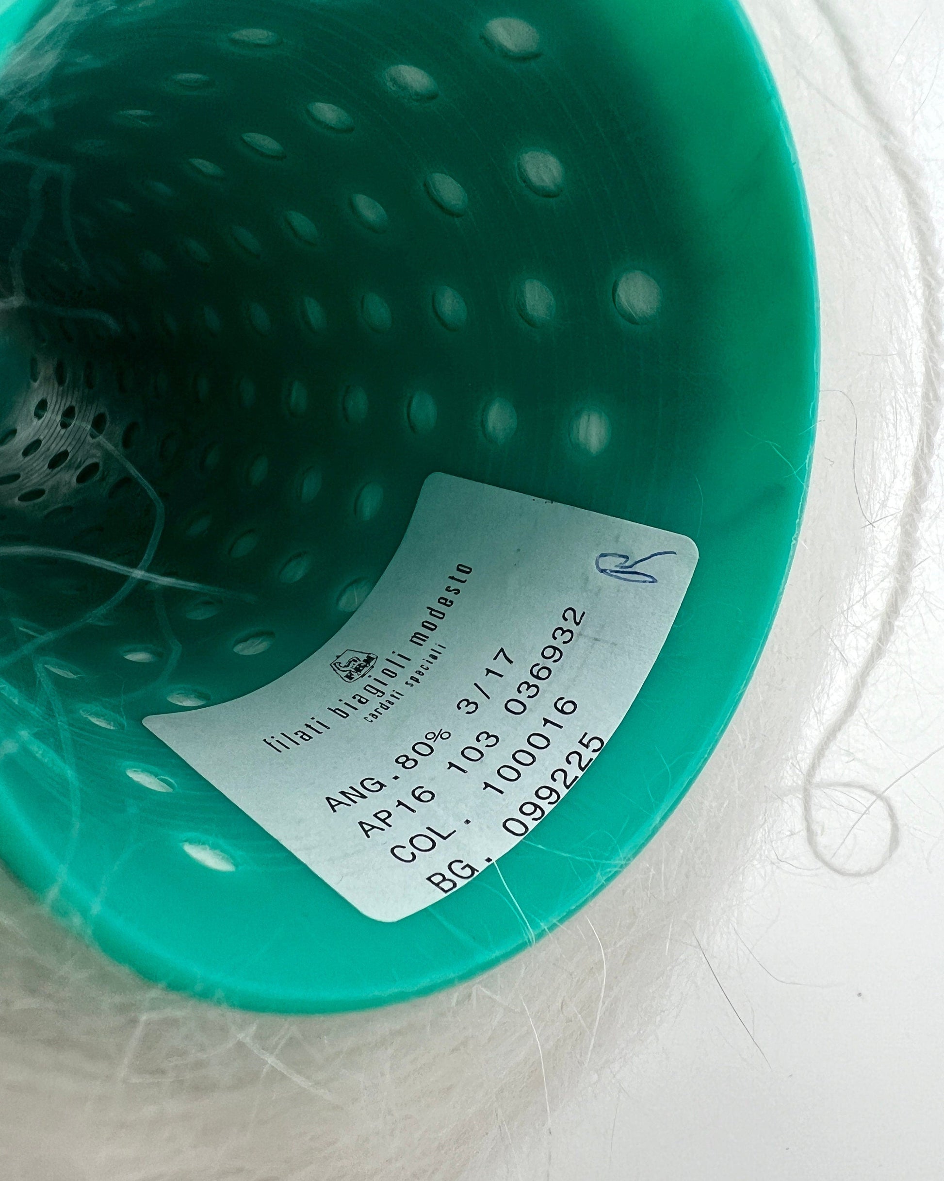 Close-up of a teal-colored product with a label on a light gray background