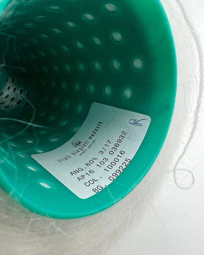Close-up of a teal-colored product with a label on a light gray background