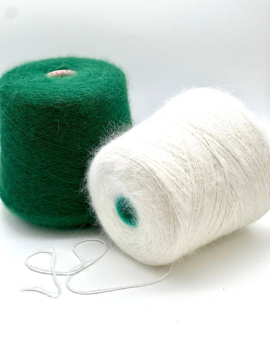 Two spools of yarn, one green and one white, on a white background.