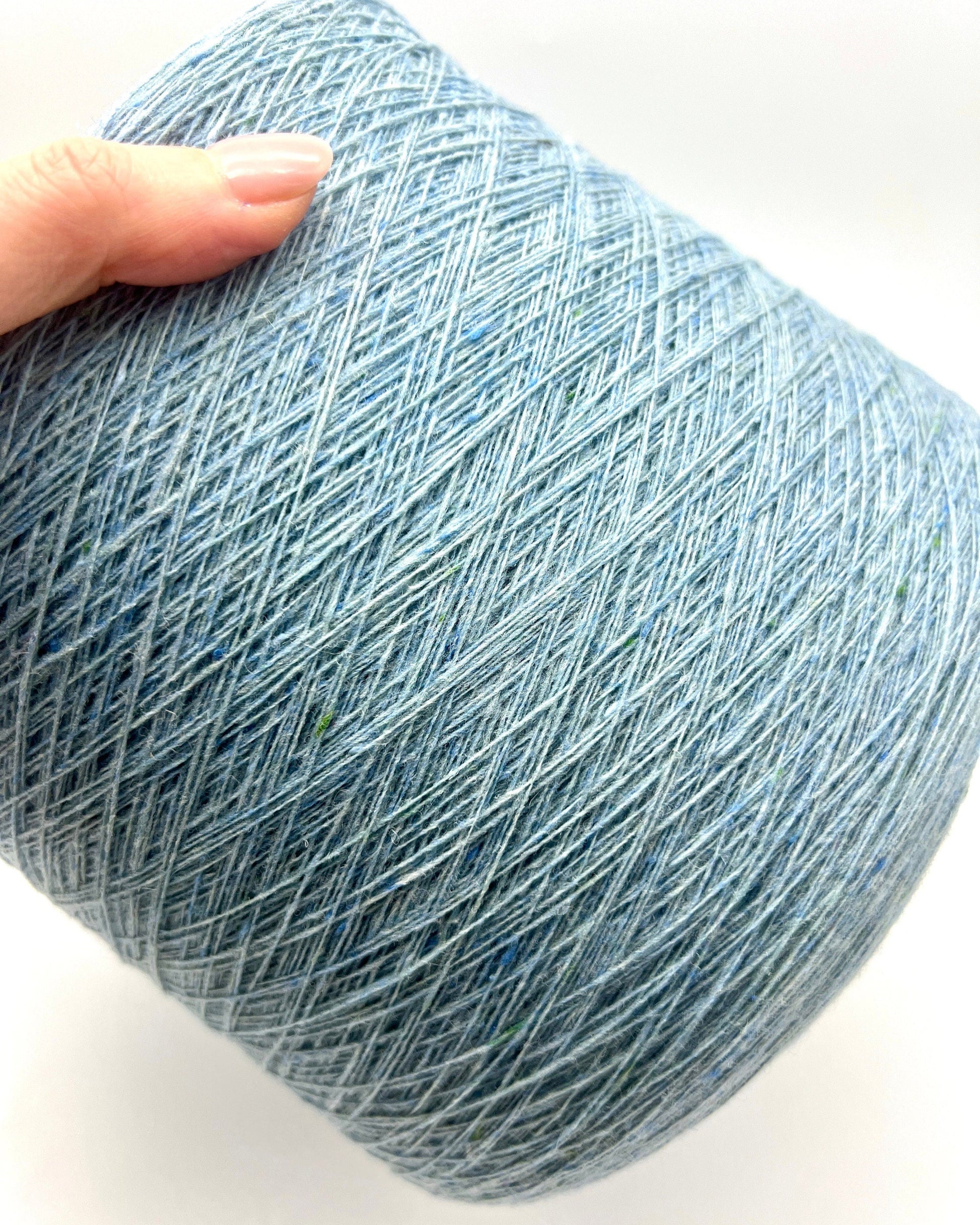 Blue skein of yarn held by a hand on a white background