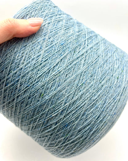 Blue skein of yarn held by a hand on a white background