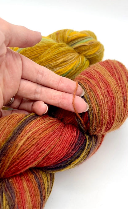 Multicolored skein of yarn held by a hand on a white background