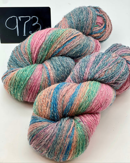 Multicolored skeins of yarn on a white background with a label reading '973'.