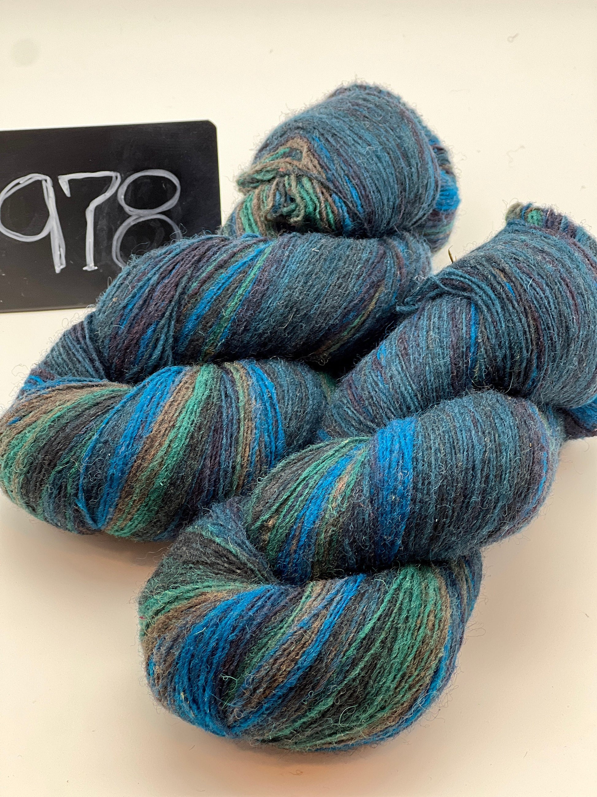 Blue and green skeins of yarn with a label in the background