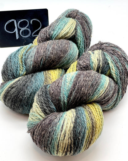 Three skeins of multicolored yarn on a white background with a label reading '982'.