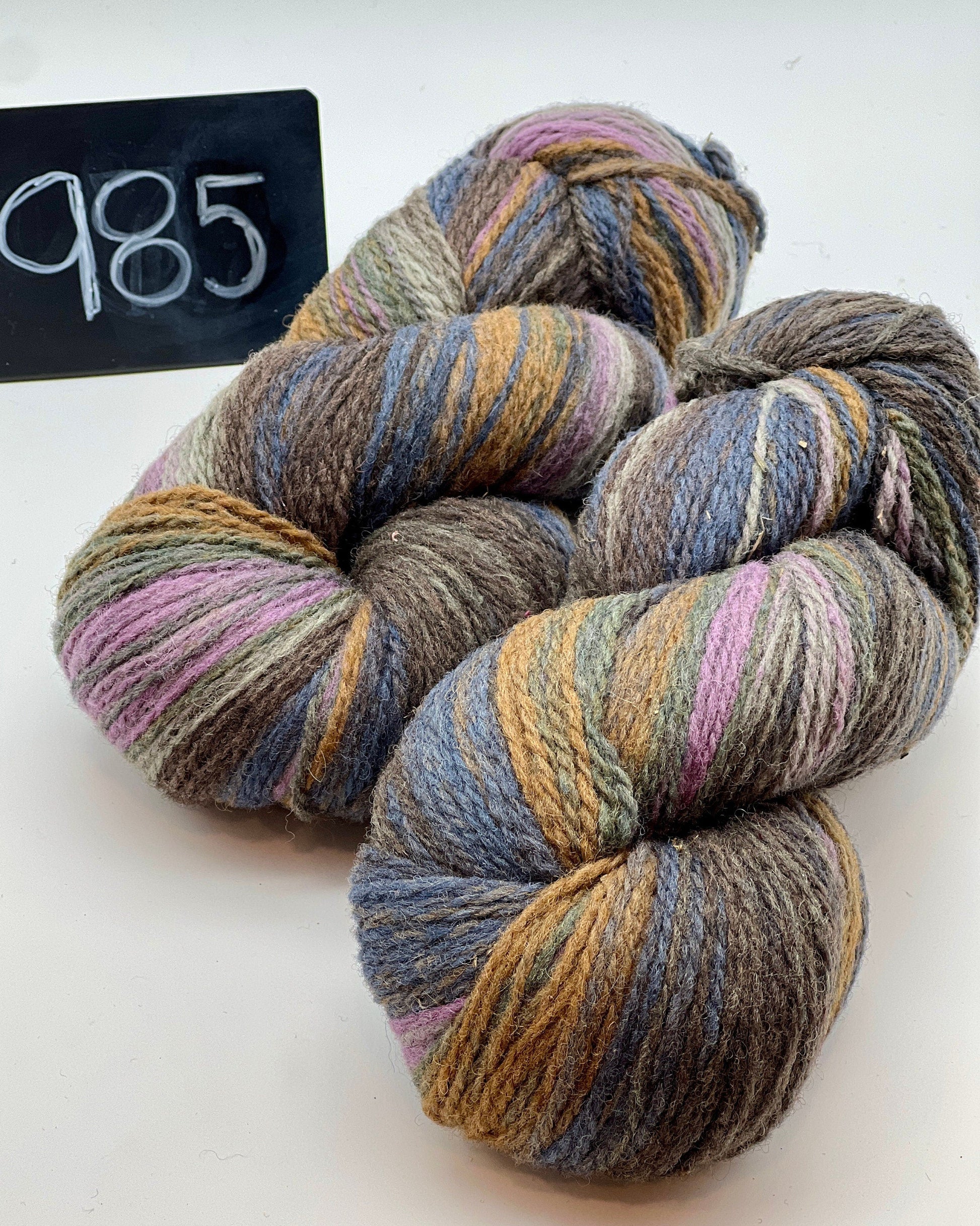 Multicolored yarn skeins on a white background with a label reading '985'.