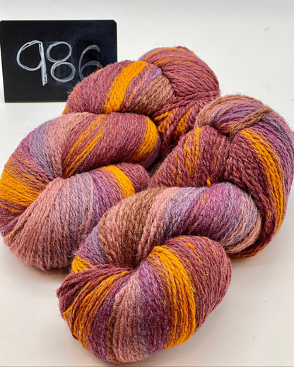 Three skeins of multicolored yarn on a white background with a black sign displaying the number 986.