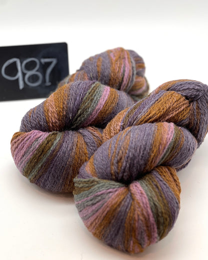 Three skeins of multicolored yarn on a white background with a label reading '987'.