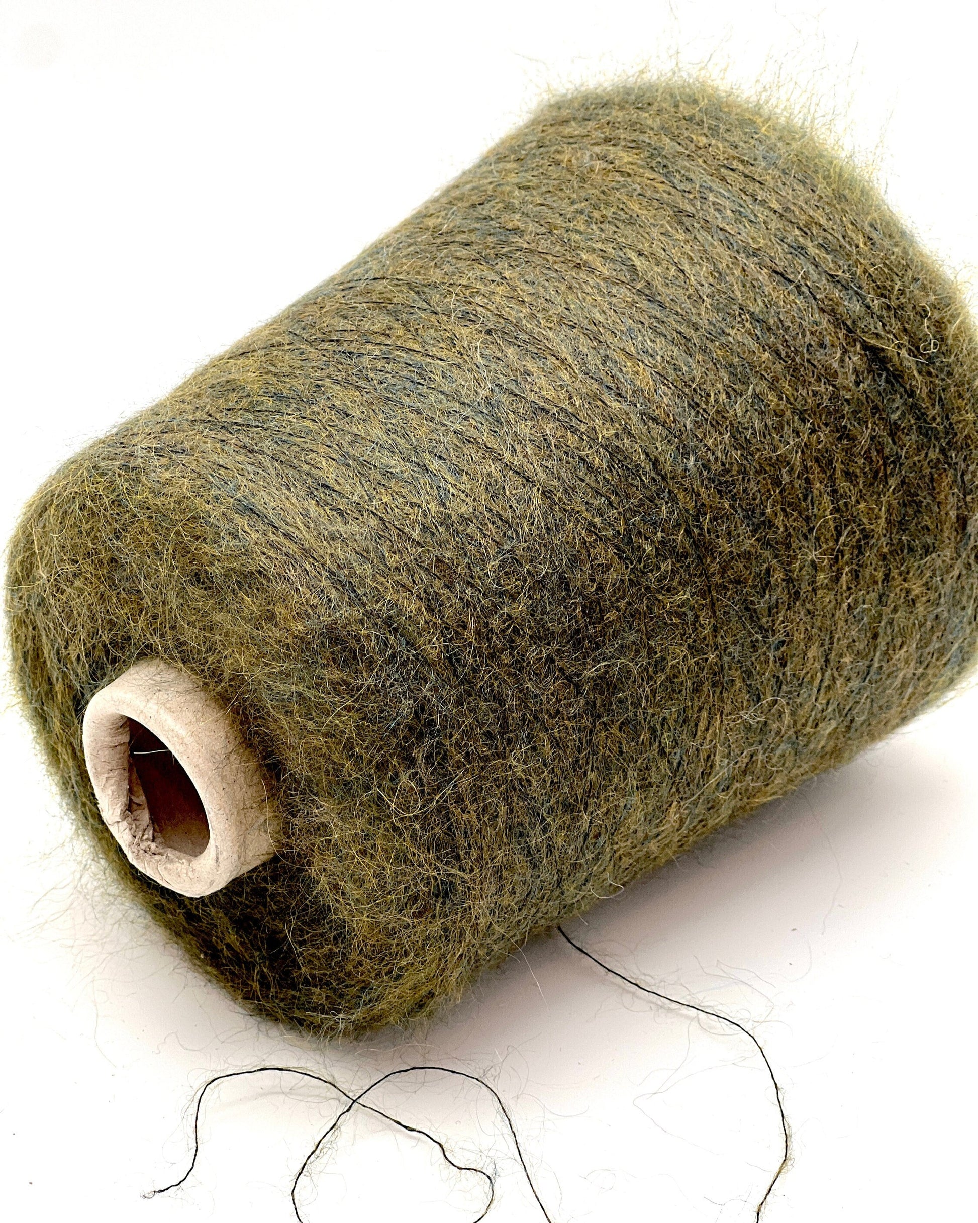 Spool of green yarn on a white background