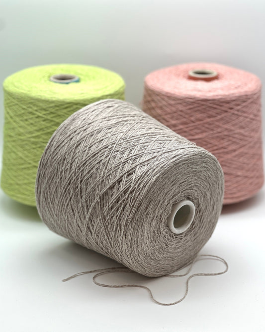 Three spools of yarn in green, gray, and pink on a white background