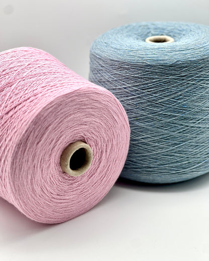 Two spools of yarn, one pink and one blue, on a light gray background.