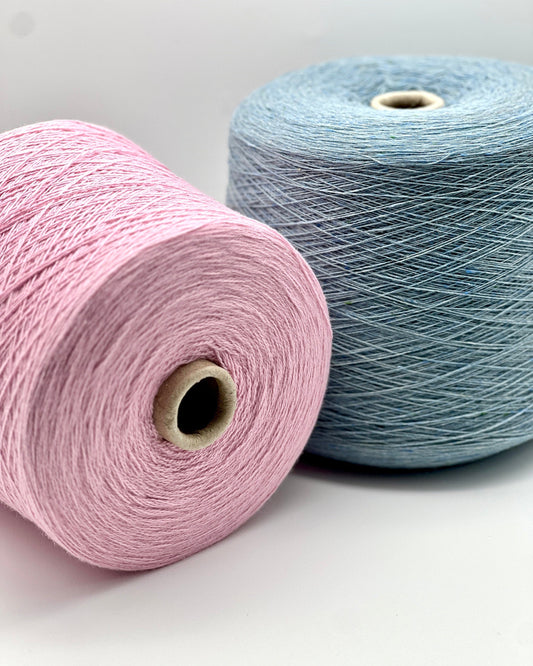 Two spools of yarn, one pink and one blue, on a light gray background.