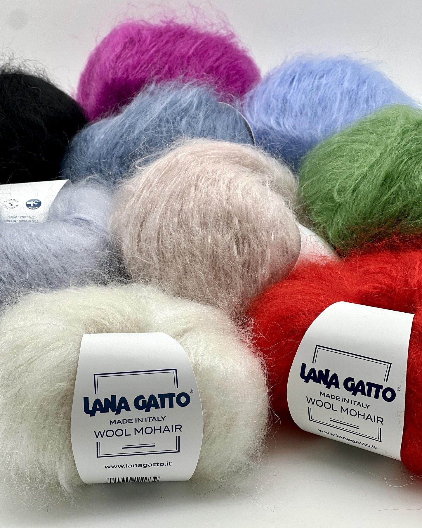 Balls of colorful wool mohair yarn with 'Lana Gatto' labels on a white background