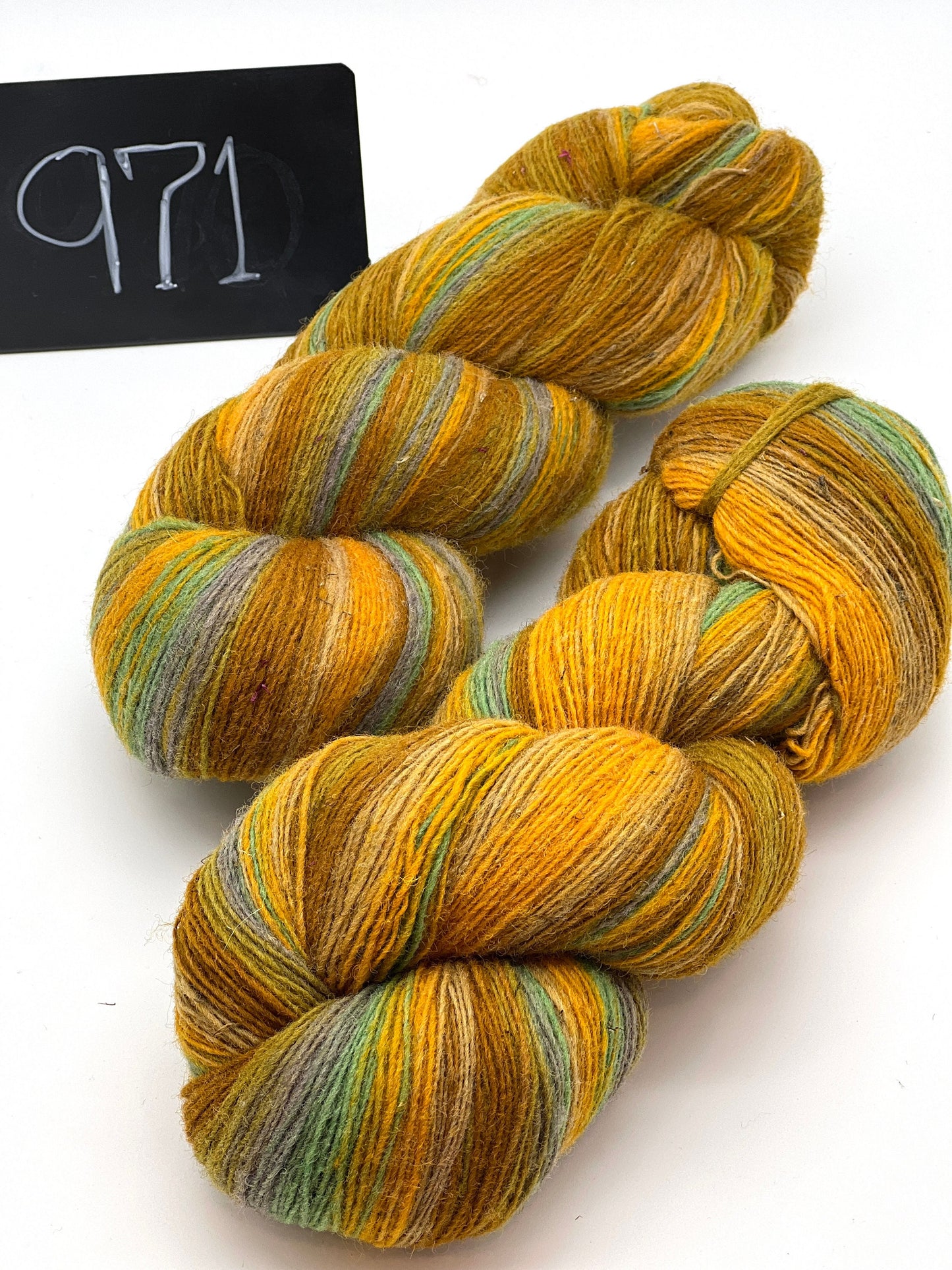 Three skeins of multicolored yarn on a white background with a black sign displaying '971'.