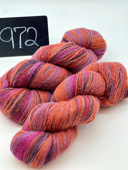 Multicolored skeins of yarn on a white background with a black sign displaying '972'.